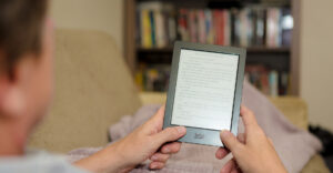 A person holding an e-reader called, Kobo, in hand.